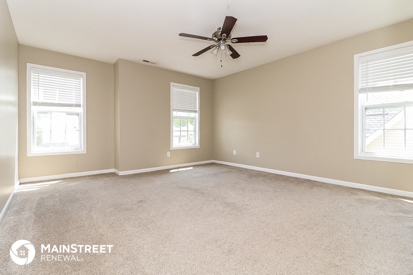 the master bedroom has a carpeted floor and a ceiling fan