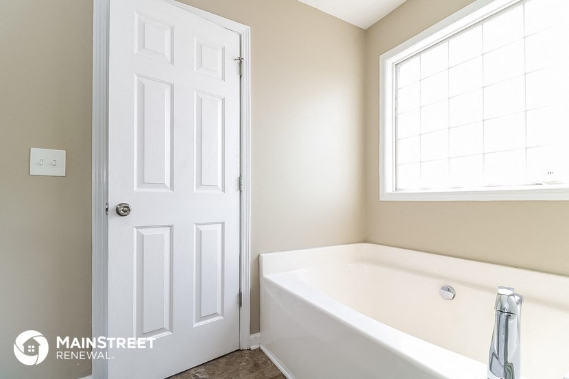 a white bathroom with a tub and a window