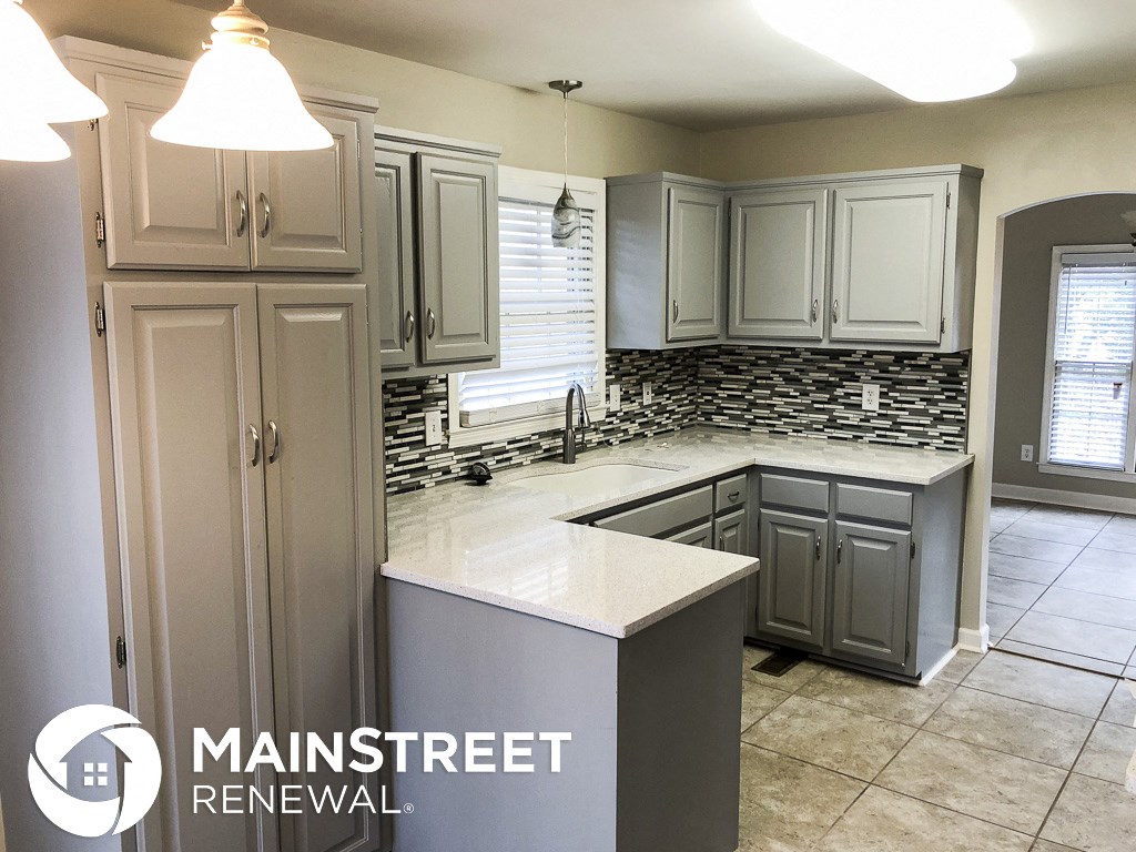 a remodeled kitchen with white cabinets and granite counter tops