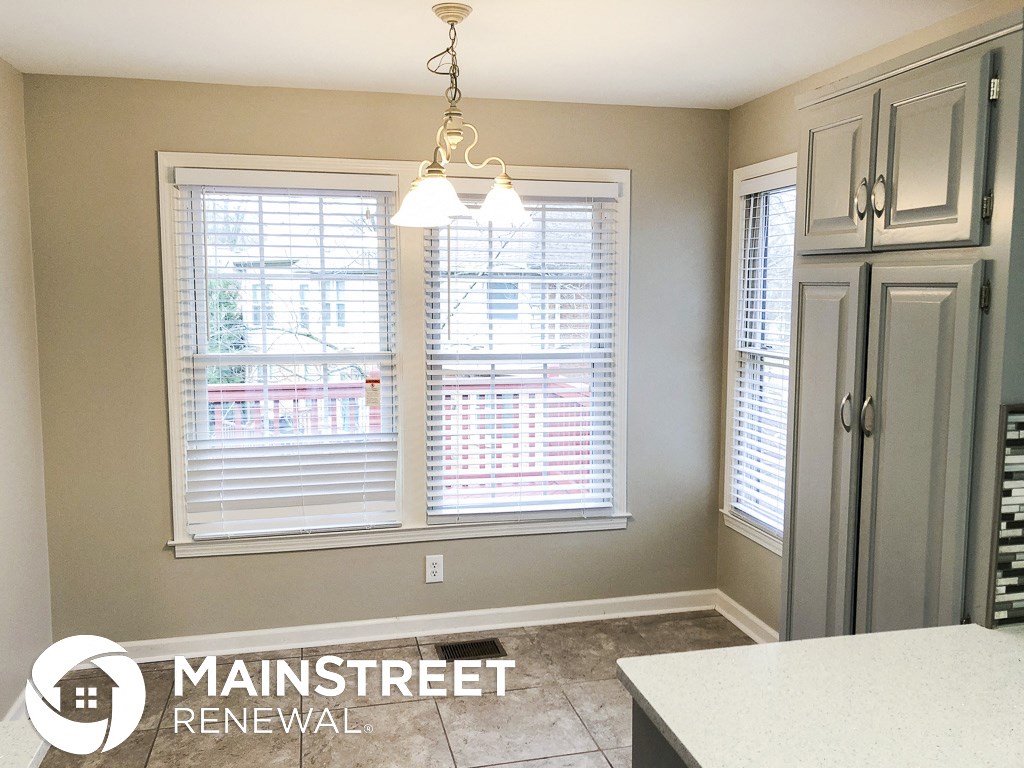 a kitchen with two windows and white cabinets and a white counter top