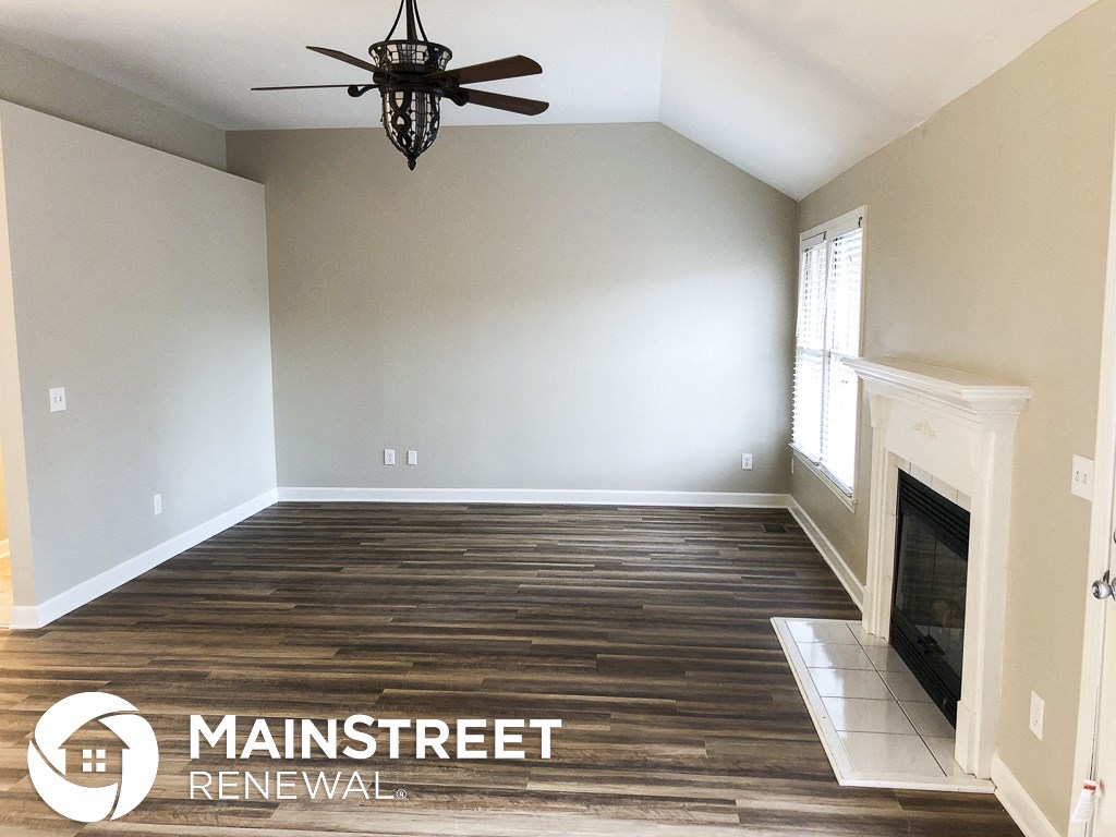 an empty living room with a fireplace and a ceiling fan