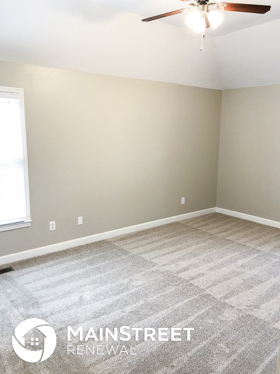 an empty room with carpet and a ceiling fan