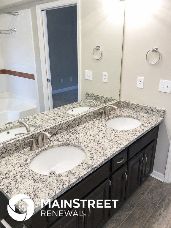 an updated bathroom with granite counter tops and two sinks