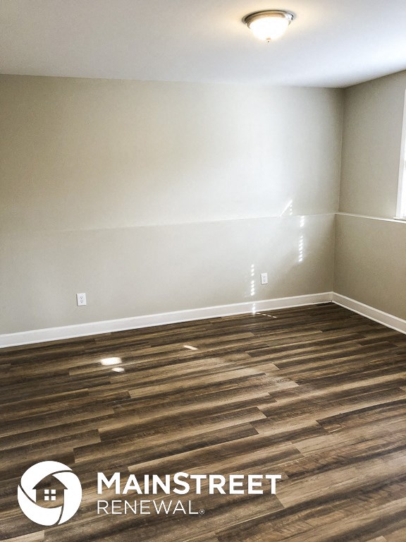 a room with wood flooring and white walls and a window
