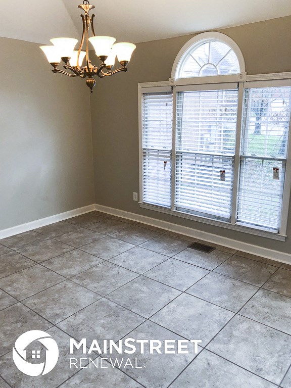 an empty room with a window and a chandelier