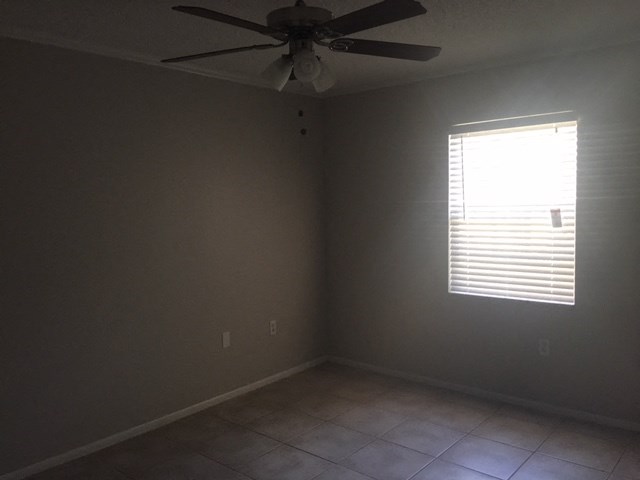 an empty room with a ceiling fan and a window