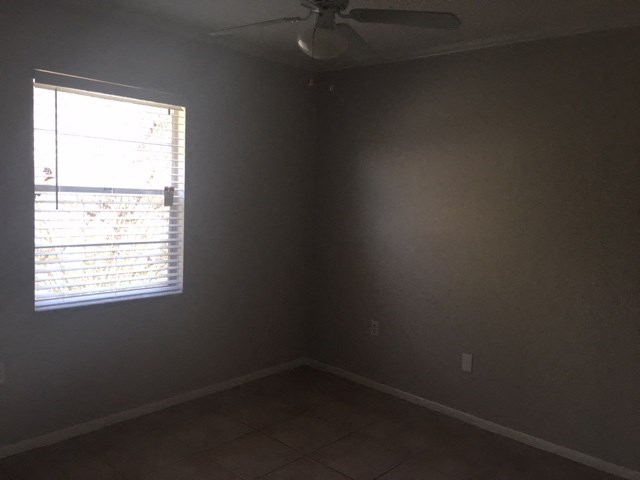 an empty room with a window and a ceiling fan