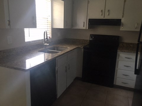 a kitchen with a sink and a black refrigerator
