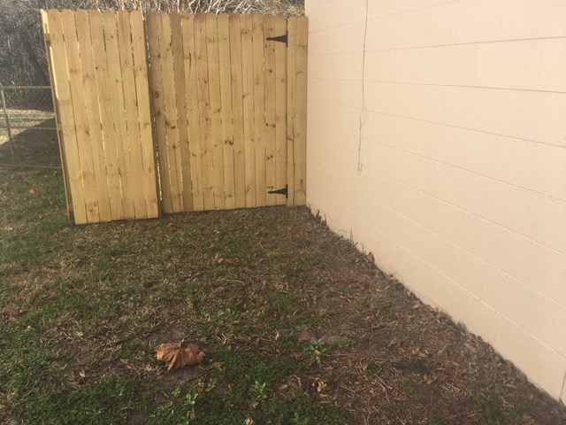 a backyard with a wooden fence and grass next to a wall