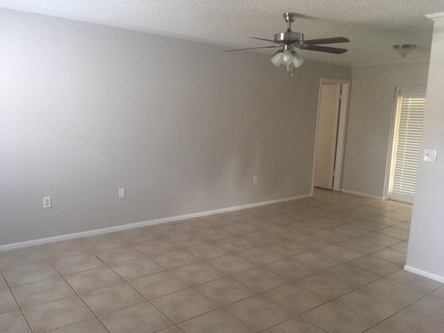 an empty living room with a ceiling fan and a tiled floor