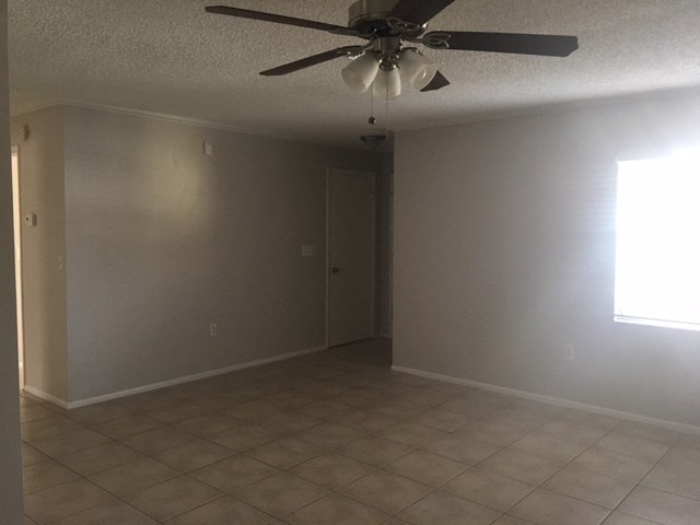 an empty living room with a ceiling fan