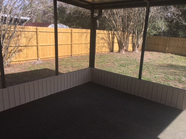 a screened in porch in a backyard with a fence