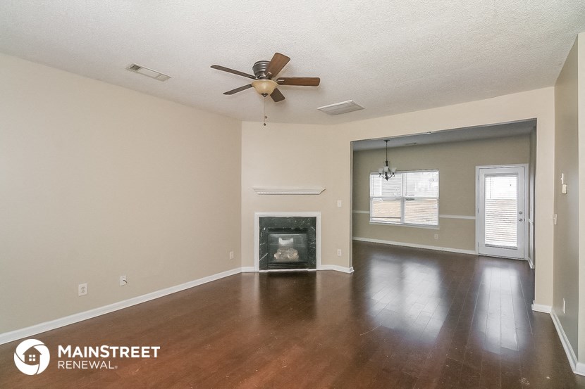 an empty living room with a fireplace and a ceiling fan