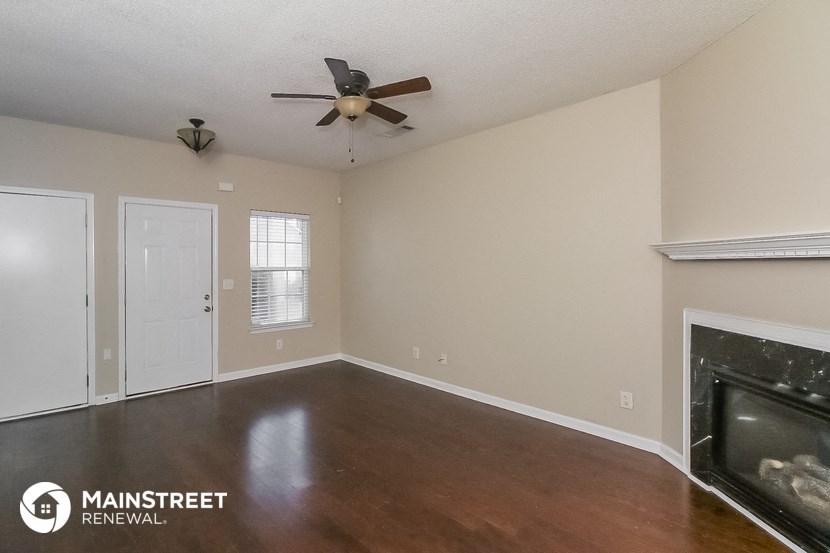 an empty living room with a ceiling fan and a fireplace