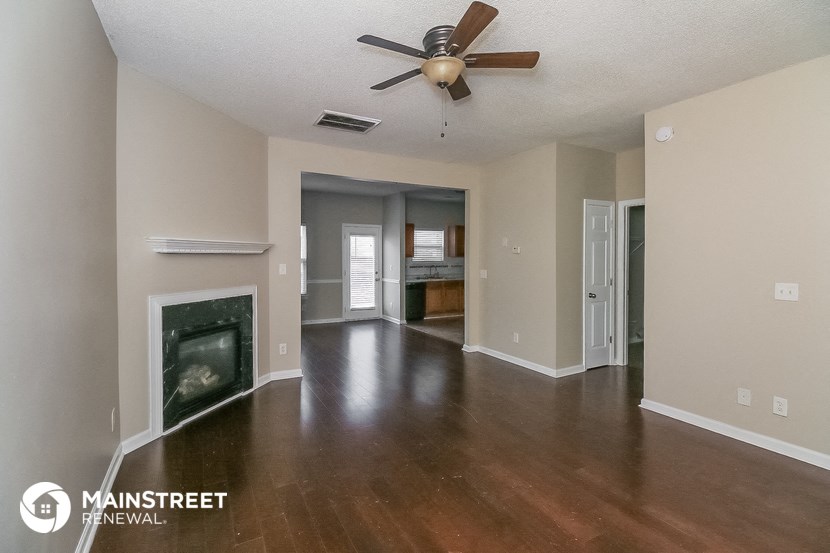 an empty living room with a fireplace and a ceiling fan