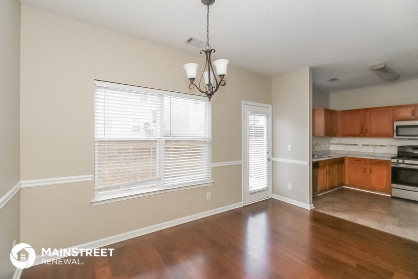 an empty living room with a large window and a kitchen