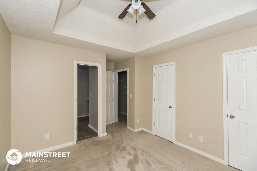 a living room with a ceiling fan and a hallway