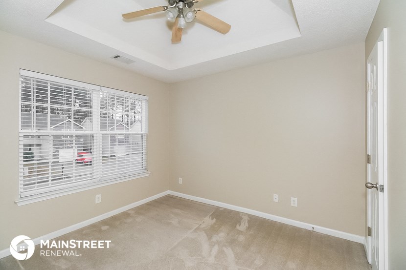 the master bedroom has a ceiling fan and a large window