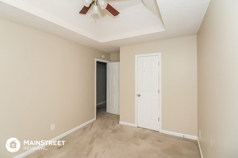 a living room with a ceiling fan and a door to a closet