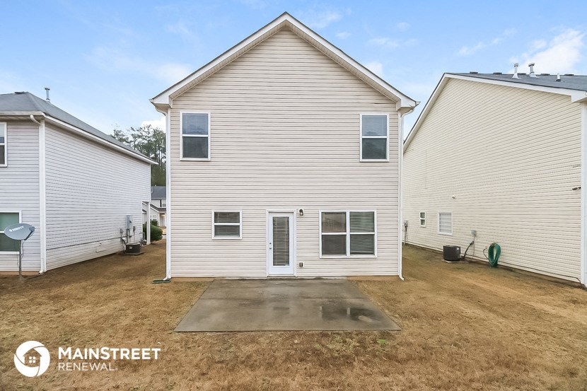 the front of a white house with a yard and a driveway