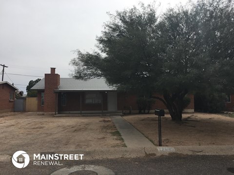 a small brick house with a tree in front of it