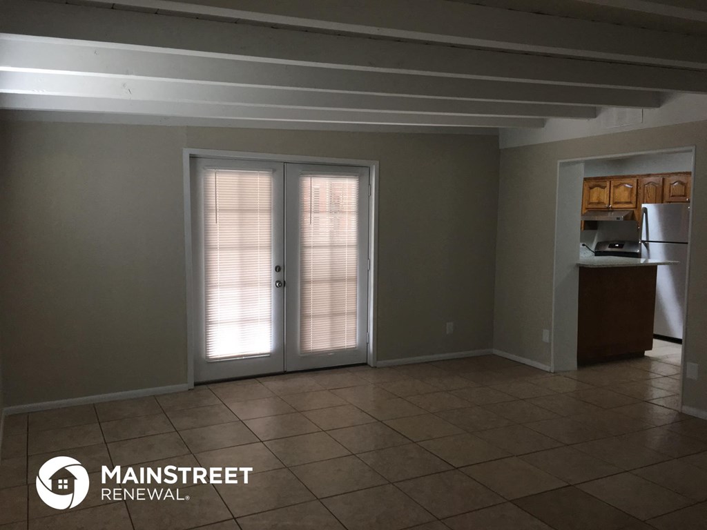 an empty living room doors and a kitchen