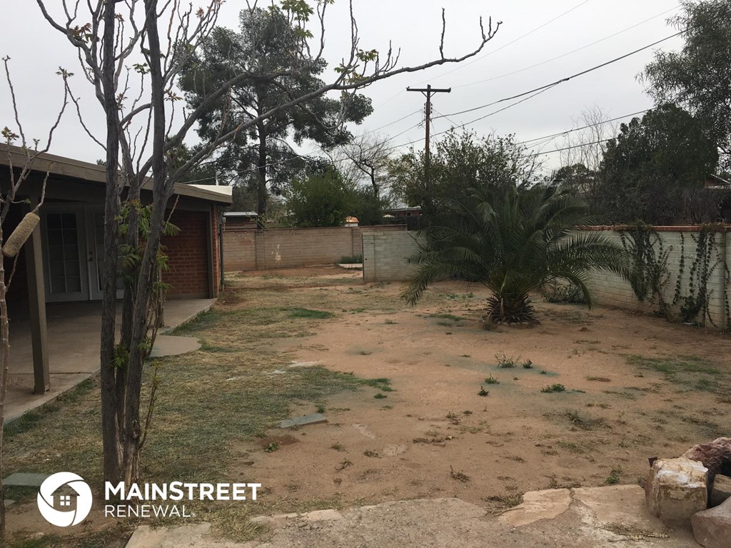 a yard with dirt and a palm tree in front of a house