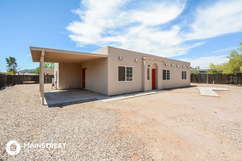 a small white house with a dirt lot and a covered porch