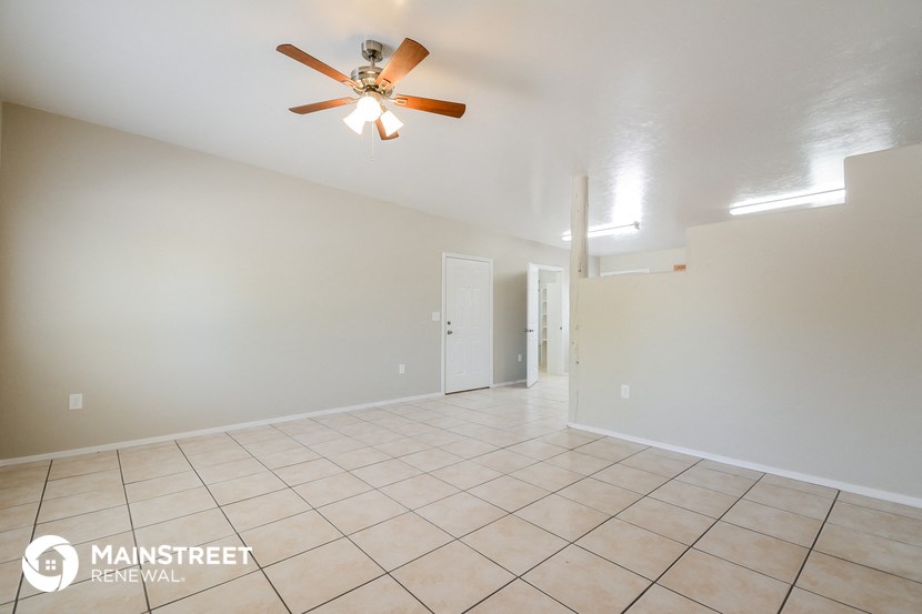 a spacious living room with tile flooring and a ceiling fan