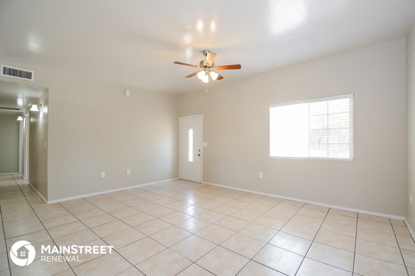the spacious living room with tile flooring and a ceiling fan