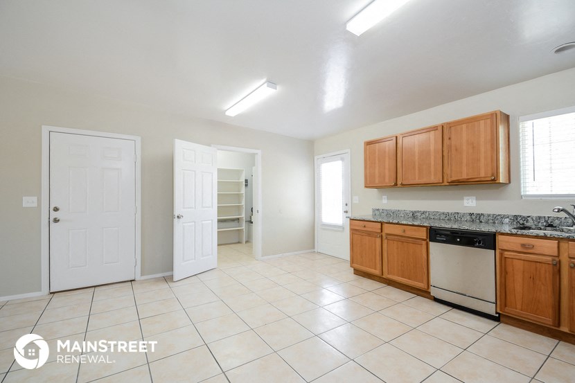 a kitchen with wooden cabinets and tiled floors and a sink and a refrigerator