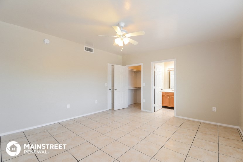 a spacious living room with tile flooring and a ceiling fan