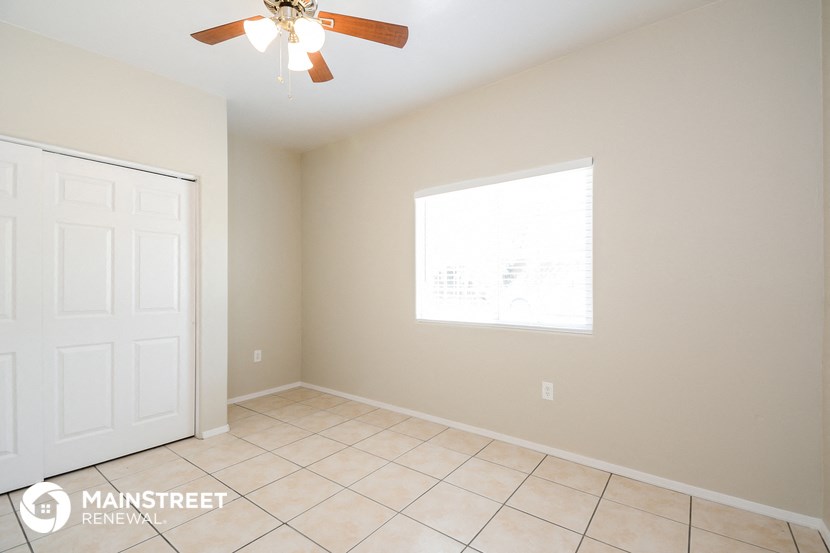 a clean and empty room with a ceiling fan and a window