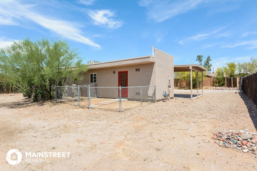 a small house with a fence and a gate in front of it