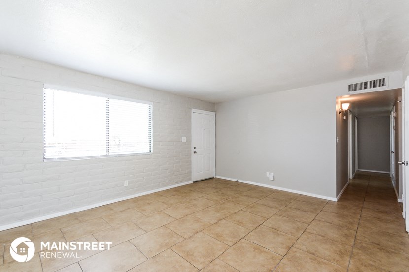 an empty living room with tile flooring and a window