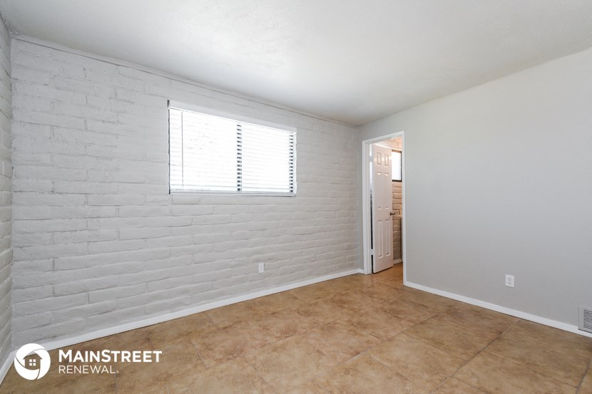 the living room of an apartment with a tile floor and a white brick wall