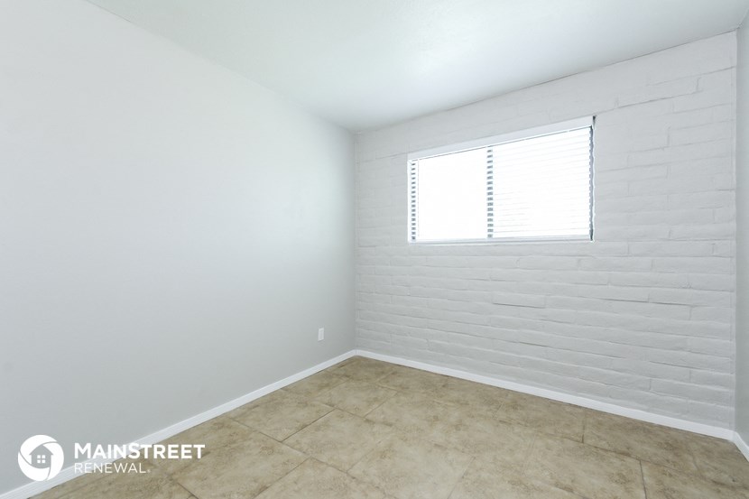 a room with white walls and tile floor and a window