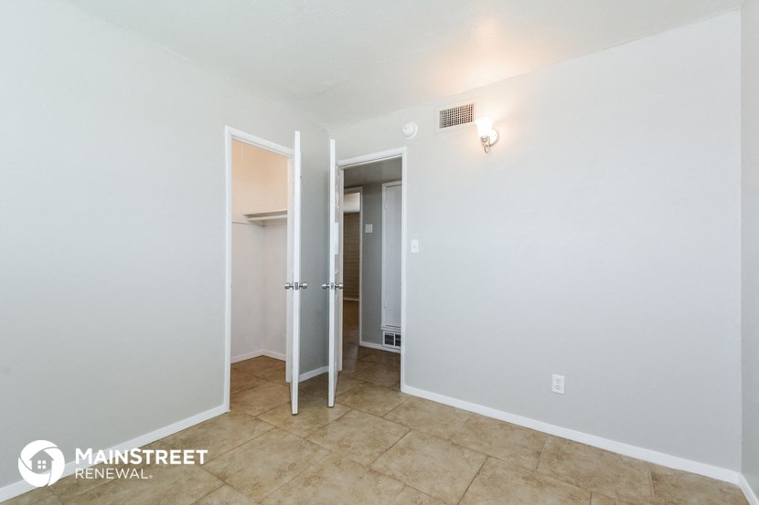 a bathroom with white walls and tile flooring and a closet