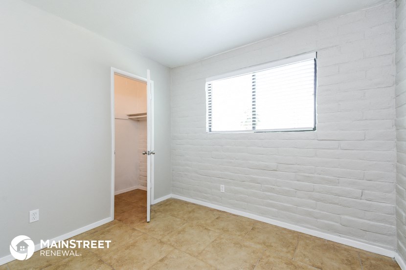 a bedroom with a white brick wall and a door to a closet