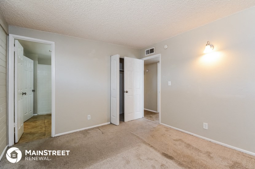 the living room of an apartment with a carpeted floor and white walls and doors