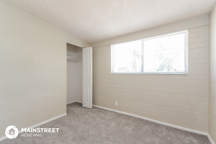 a bedroom with a large window and a door to a closet