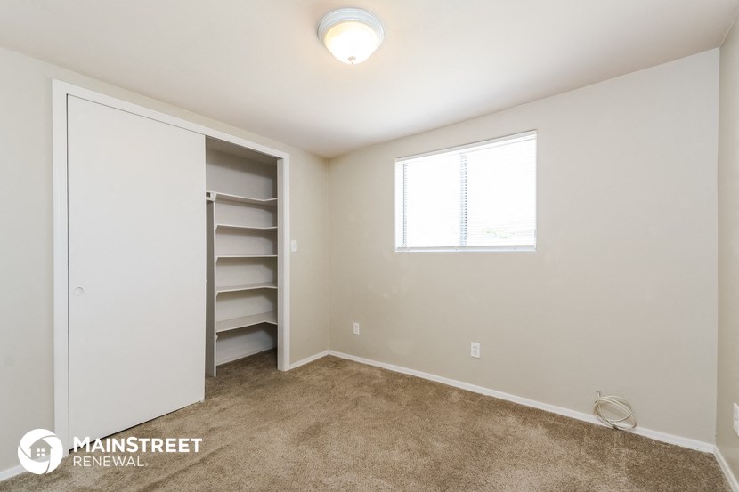a bedroom with a closet and a window and a carpeted floor