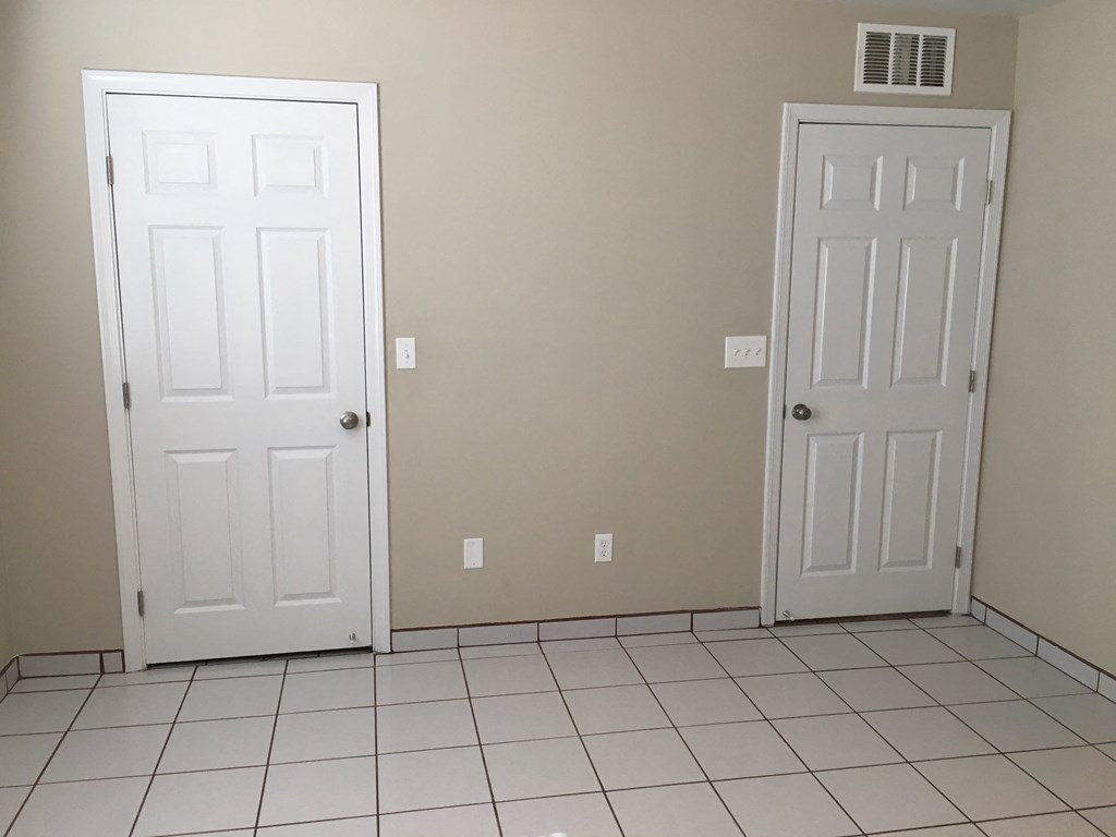 a room with two doors and a white tiled floor