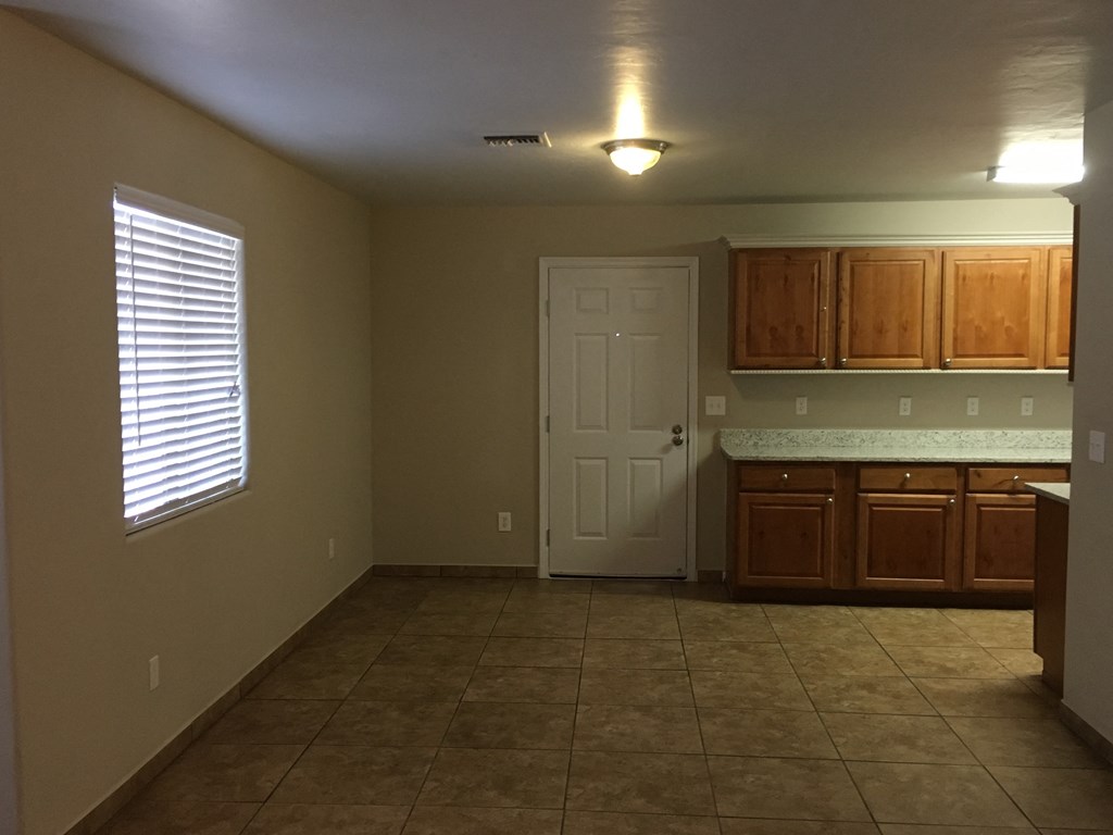 an empty kitchen with tile flooring and a white door