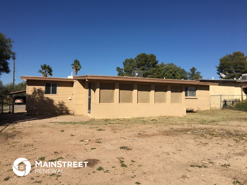 an old house with a dirt lot and palm trees