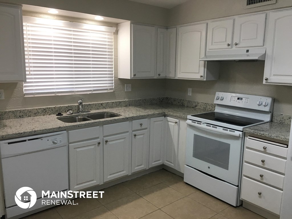 a white kitchen with white appliances and granite counter tops