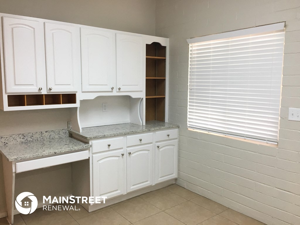 a kitchen with white cabinets and counters and a window