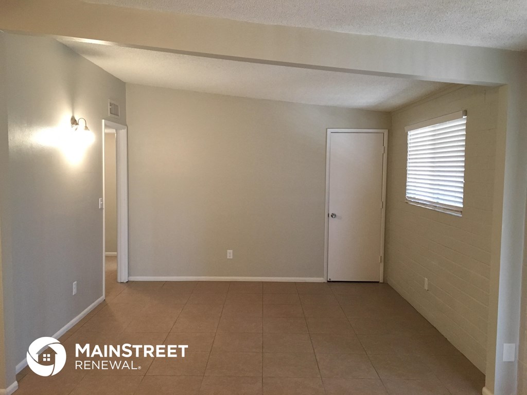 an empty living room with a white door and a tiled floor