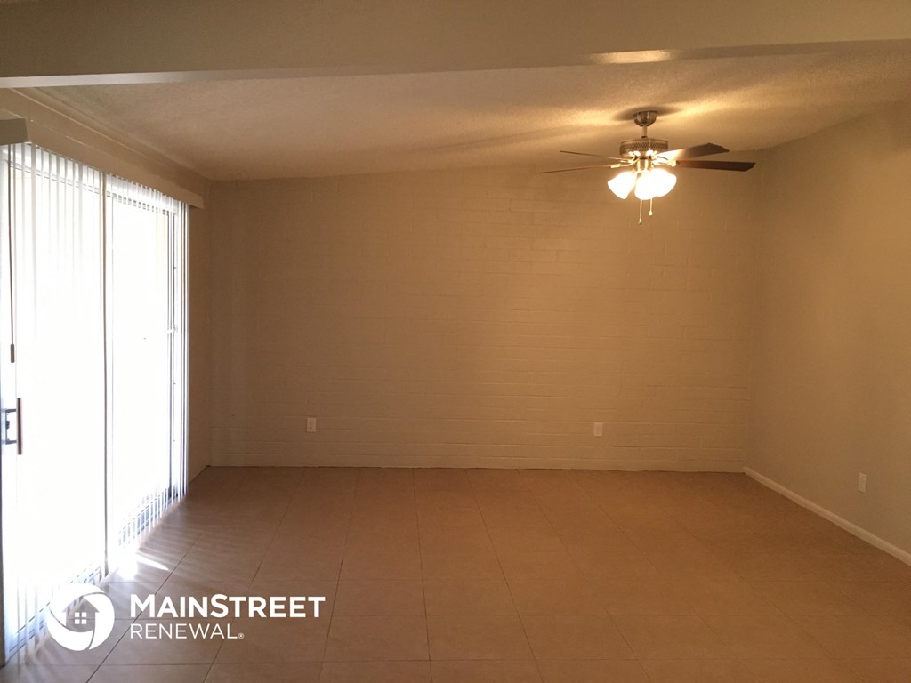 an empty living room with a ceiling fan