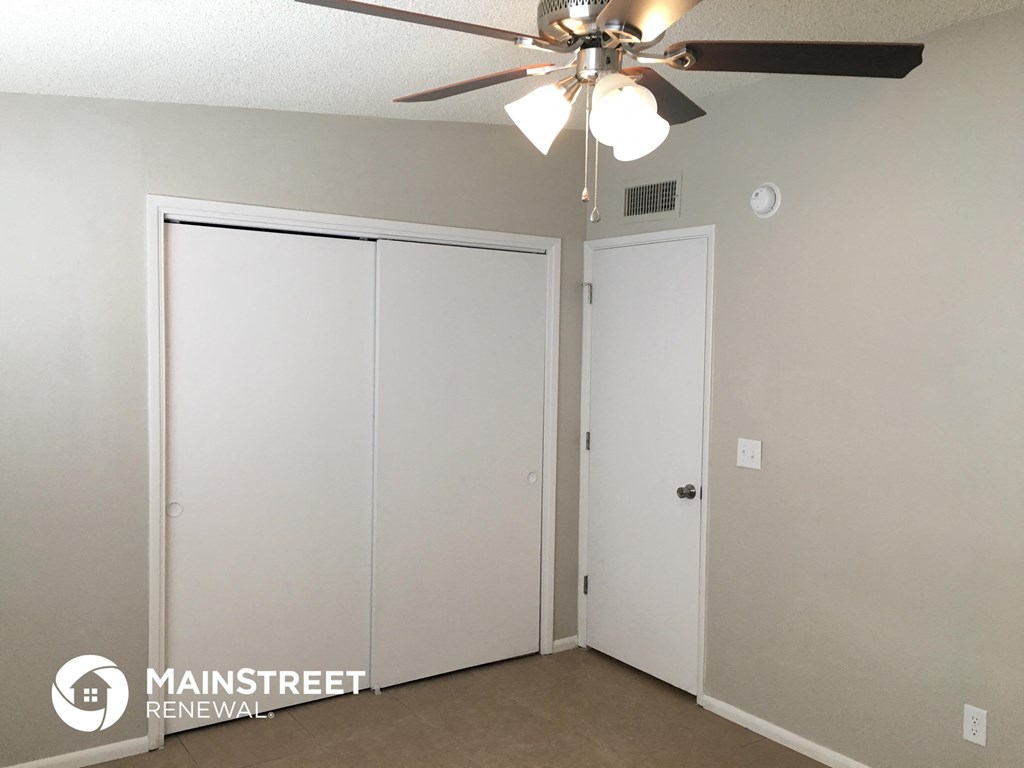 an empty room with a ceiling fan and two closet doors